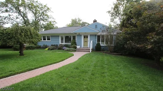 a front view of a house with a garden and trees