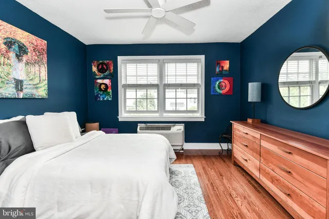 a spacious bedroom with a bed a mirror on the dresser and a chandelier