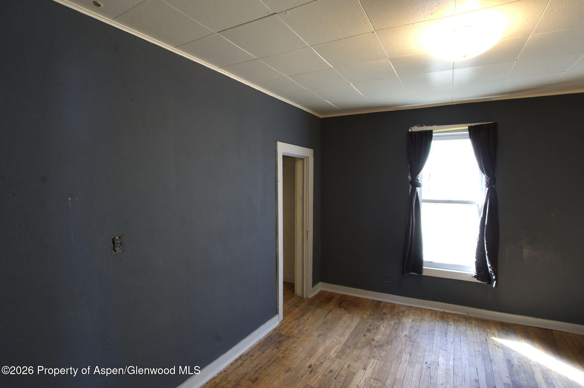 995 Colorado Street Craig, CO 81625 - Photo 6 of 21 an empty room with wooden floor and windows