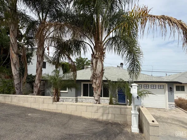 a view of a house with a yard and palm trees