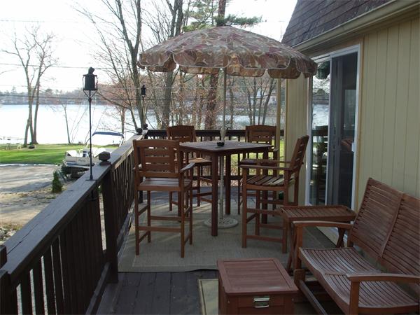 a view of a patio with table and chairs under an umbrella with wooden floor and fence