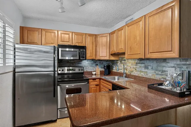 a kitchen with stainless steel appliances granite countertop a refrigerator a sink a stove and cabinets