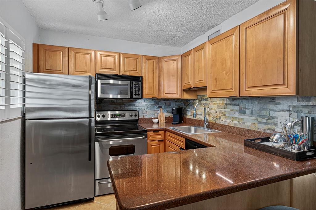 a kitchen with stainless steel appliances granite countertop a refrigerator a sink a stove and cabinets