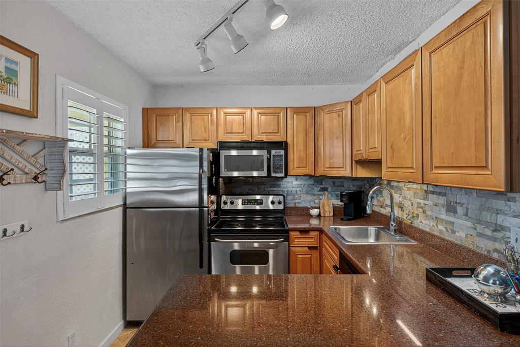 2660 Northeast 8th Avenue, Unit 208 Wilton Manors, FL 33334 - Photo 3 of 49 a kitchen with a refrigerator a stove a sink dishwasher and wooden cabinets with wooden floor