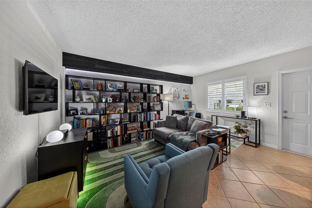 2660 Northeast 8th Avenue, Unit 208 Wilton Manors, FL 33334 - Photo 8 of 49 a living room with furniture a flat screen tv and a bookshelf