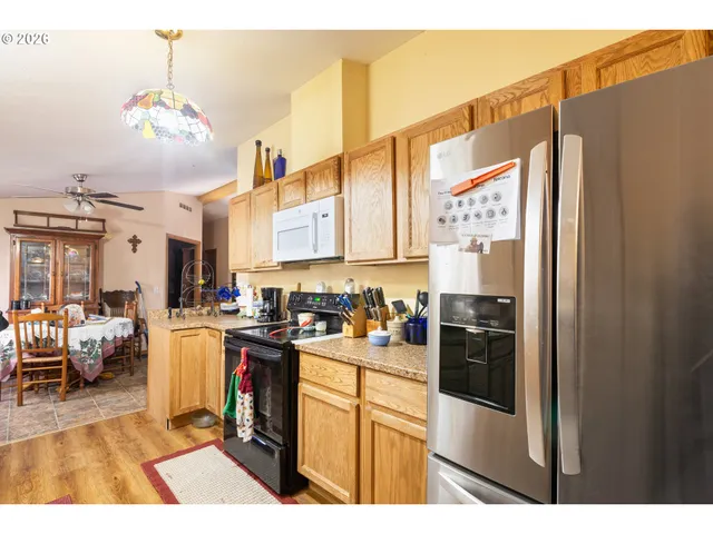 a kitchen with stainless steel appliances kitchen island granite countertop a refrigerator a sink dishwasher with a dining table and chairs