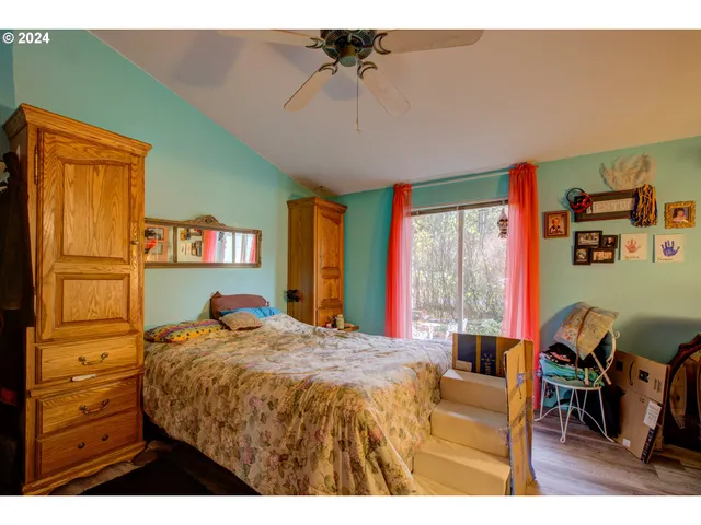 a bedroom with a bed a dresser next to a window