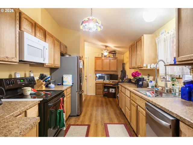 a kitchen with kitchen island granite countertop a sink appliances cabinets and a counter top space