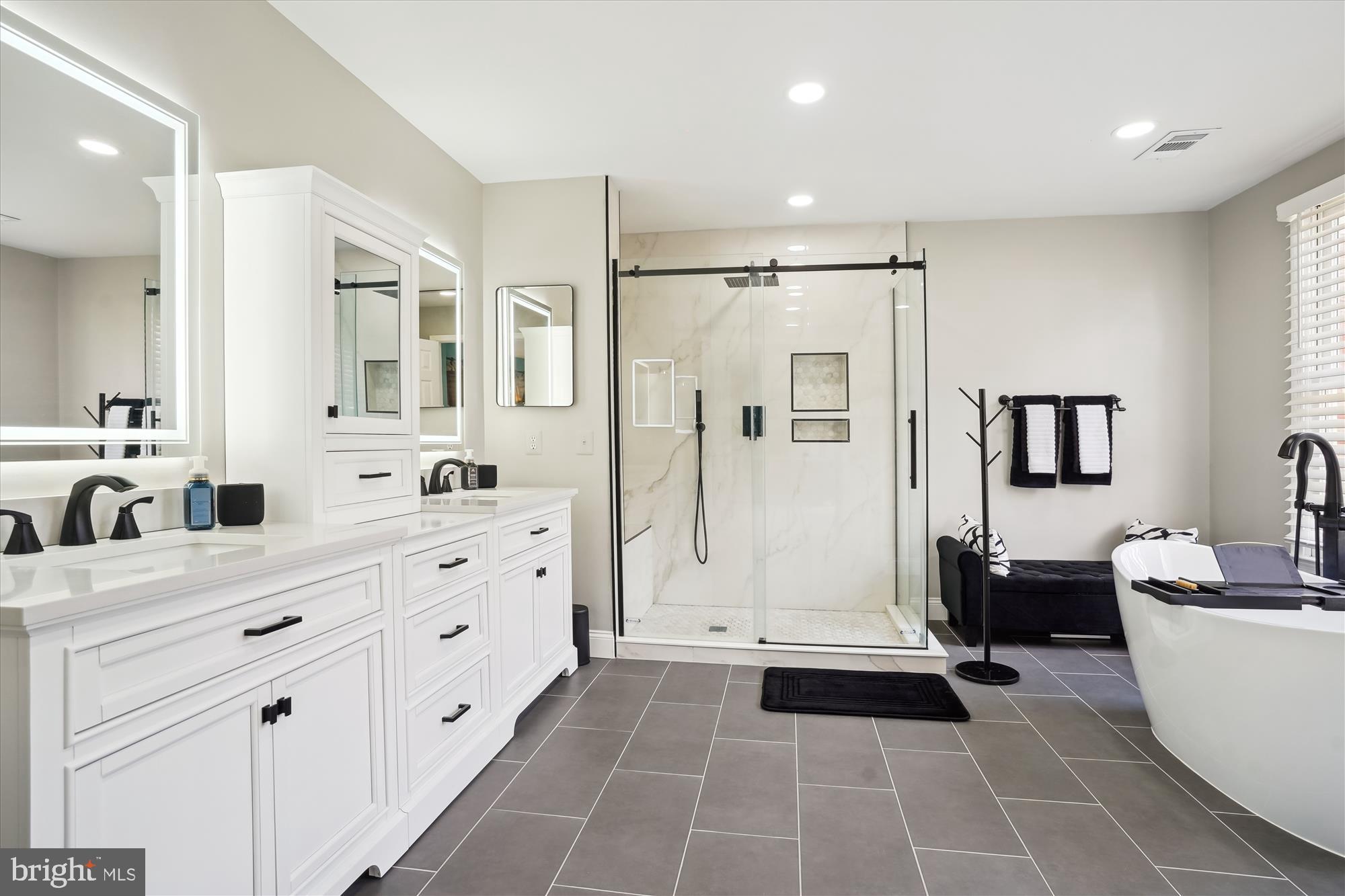 8535 Oak Chase Circle Fairfax Station, VA 22039 - Photo 33 of 62 a bathroom with a double vanity sink a mirror a bathtub and a shower