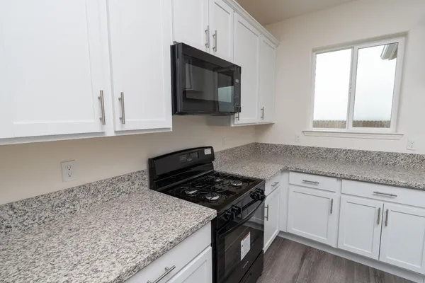 a kitchen with granite countertop white cabinets and black appliances
