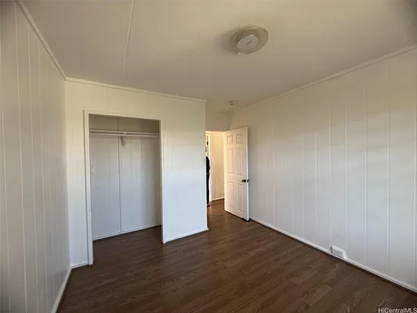 a view of an empty room with wooden floor and closet