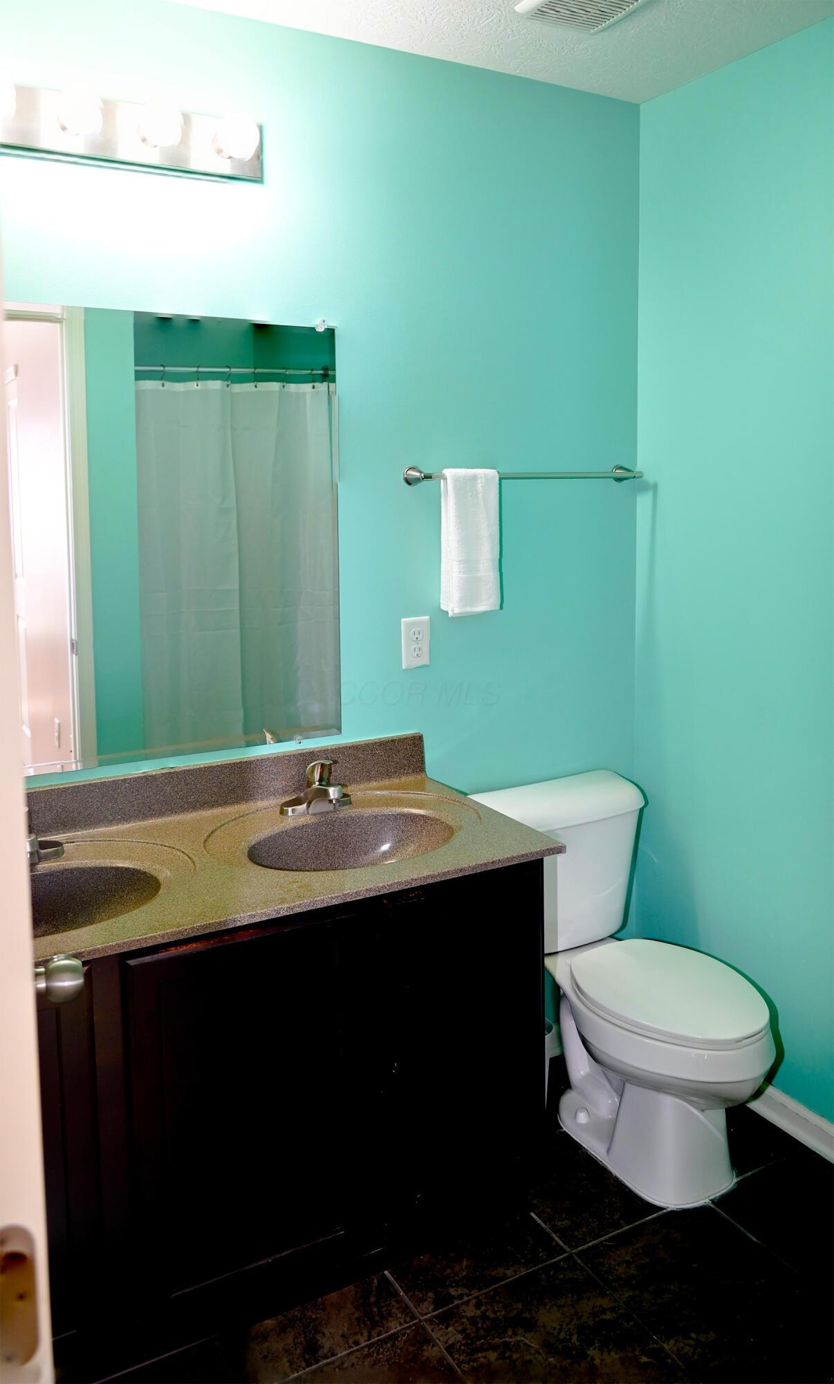 8289 Bruntsfield Road Columbus, OH 43235 - Photo 22 of 36 Private ensuite bathroom featuring a spacious double-sink vanity, generous counter space, dark wood cabinetry, tile flooring, and direct access from the bedroom. Designed for comfort and convenience with ample storage and room for daily routines.