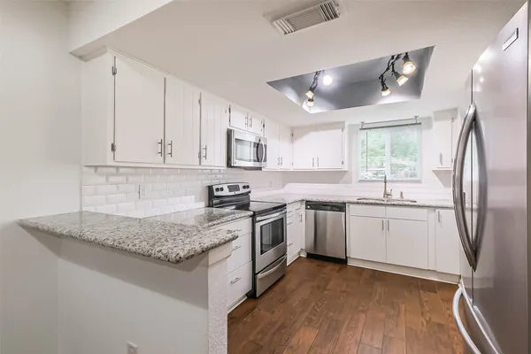 a kitchen with kitchen island granite countertop a sink cabinets and stainless steel appliances