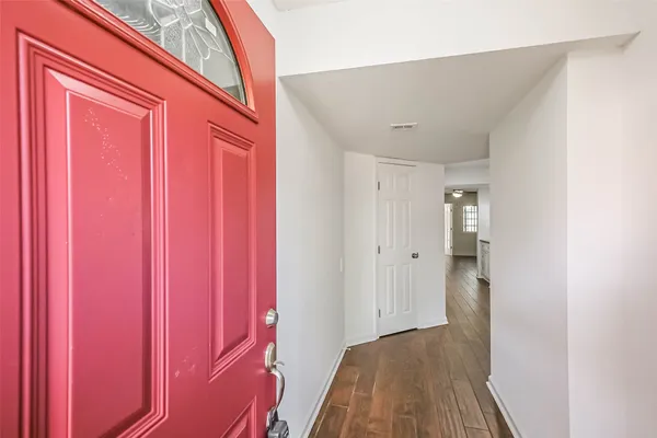 a view of a hallway with wooden floor and a bathroom
