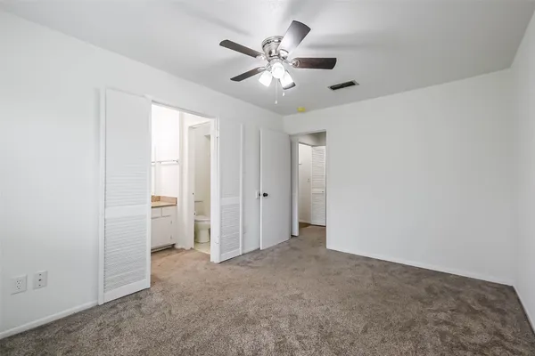 an empty room with closet and a ceiling fan
