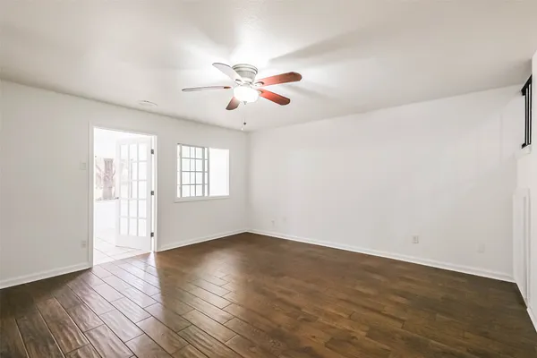 a view of empty room with wooden floor and fan