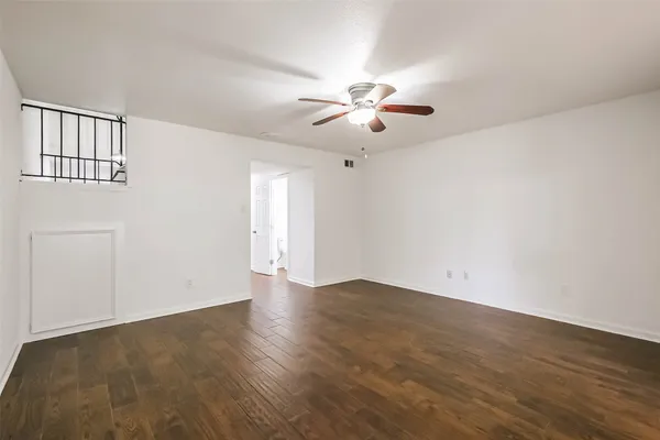 an empty room with wooden floor chandelier fan and windows