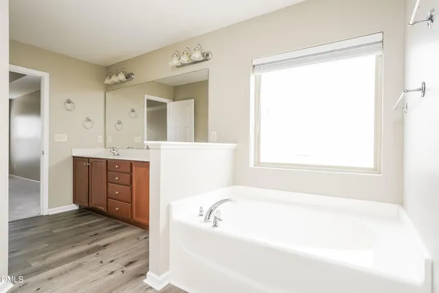 a spacious bathroom with a tub sink and mirror