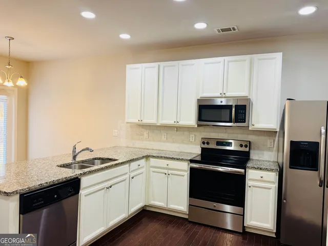 a kitchen with granite countertop white cabinets and stainless steel appliances