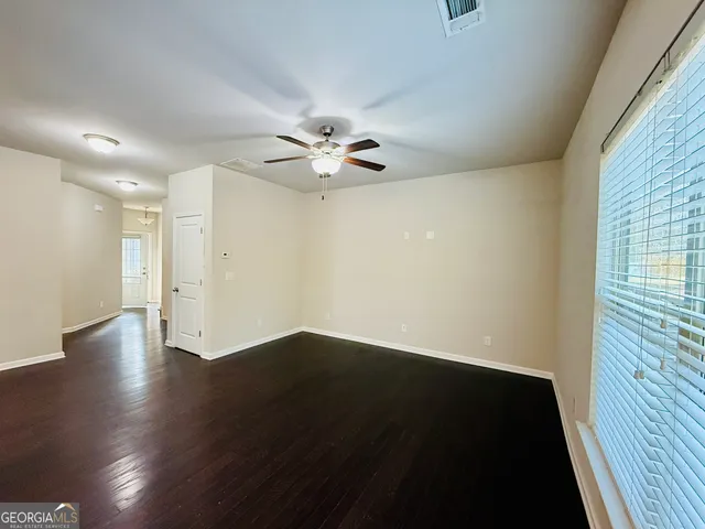 an empty room with wooden floor and fan