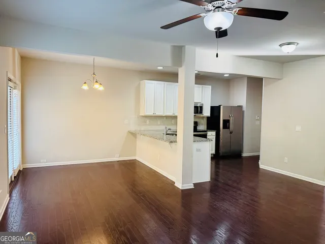 a view of a kitchen with a refrigerator a ceiling fan and wooden floor