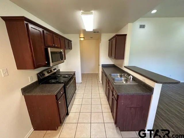 a kitchen with stainless steel appliances granite countertop a stove a sink and a microwave