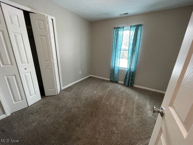 5514 Linn Road Amherst, OH 44001 - Photo 9 of 16 Unfurnished bedroom featuring dark colored carpet, a textured ceiling, and a closet