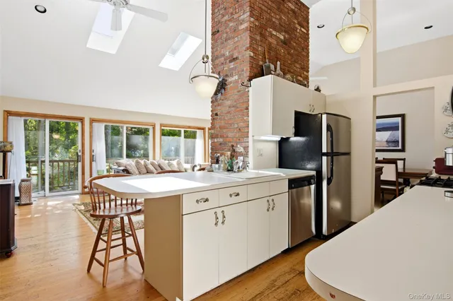 a kitchen with stainless steel appliances a dining table chairs stove refrigerator and cabinets