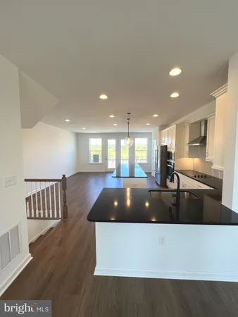 a living room with stainless steel appliances furniture wooden floor and a view of kitchen