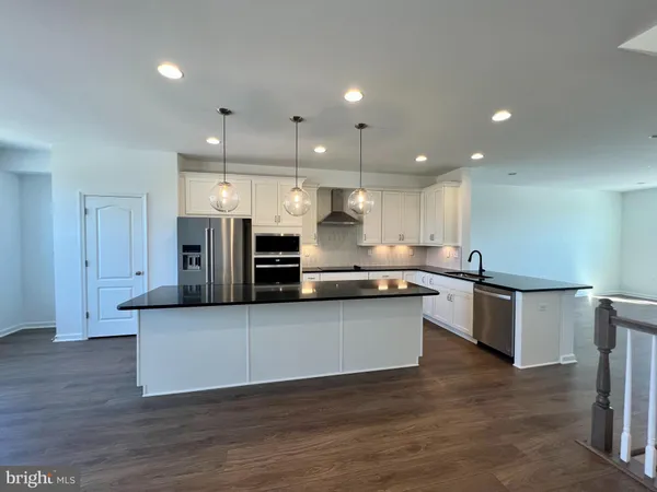 a large kitchen with stainless steel appliances kitchen island a large counter top and wooden floors