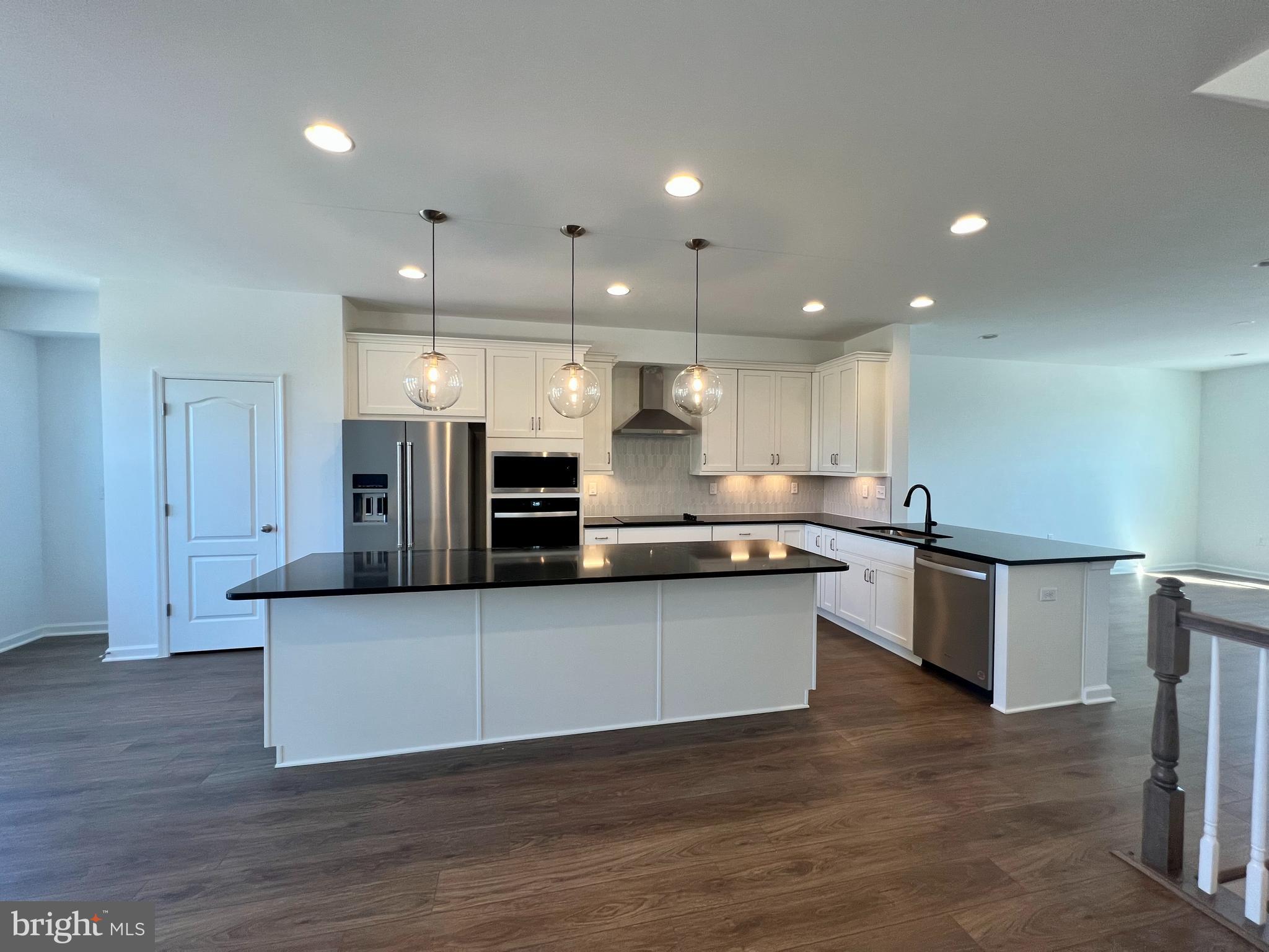 3141 Eton Place Winchester, VA 22601 - Photo 8 of 41 a large kitchen with stainless steel appliances kitchen island a large counter top and wooden floors