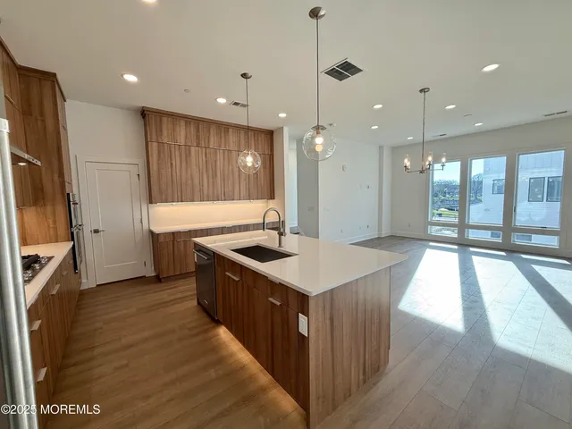 a kitchen with stainless steel appliances granite countertop a sink a stove and a wooden floors