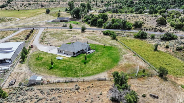 3123 East Riverdale Road Preston, ID 83263 - Photo 51 of 52 Expansive property featuring a single-story residence with a gray shingle roof, a large green lawn, and a paved driveway