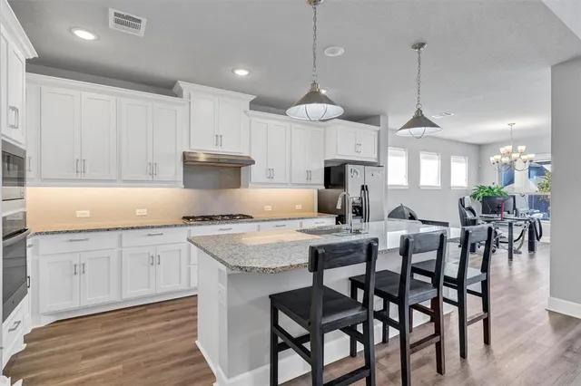 a kitchen with stainless steel appliances granite countertop a kitchen island a stove and a wooden floor
