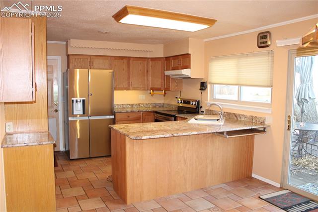 8340 Piute Road Colorado Springs, CO 80926 - Photo 15 of 48 Kitchen with stainless steel appliances, a peninsula, crown molding, light stone countertops