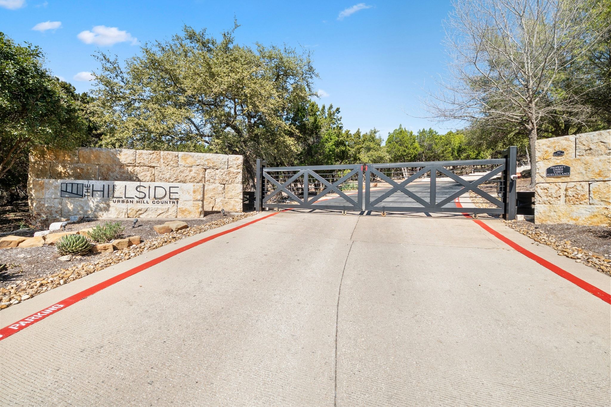8110 Ranch Road 2222, Unit 92 Austin, TX 78730 - Photo 40 of 40 Stone entrance wall featuring integrated signage, flanked by a dark wood-finish gate