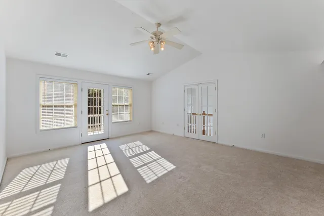 an empty room with windows and ceiling fan
