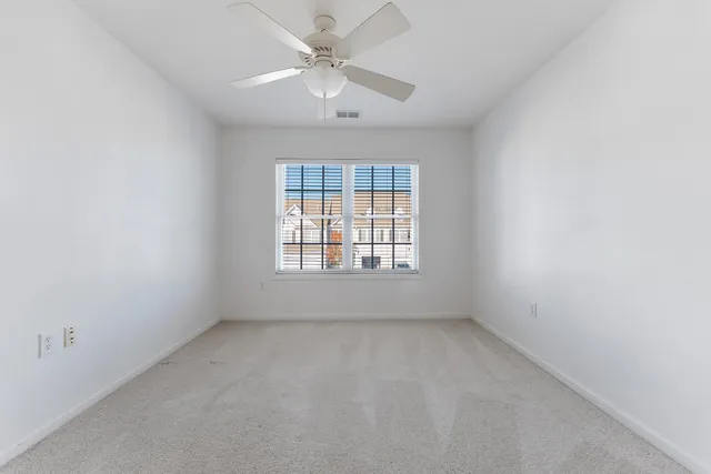 an empty room with a window and a fan