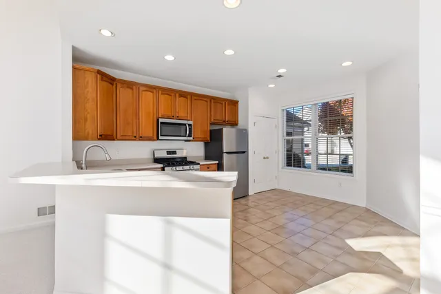 a large white kitchen with kitchen island granite countertop a stove top oven a sink a counter space and cabinets