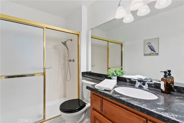 a bathroom with a granite countertop sink a toilet a mirror and shower