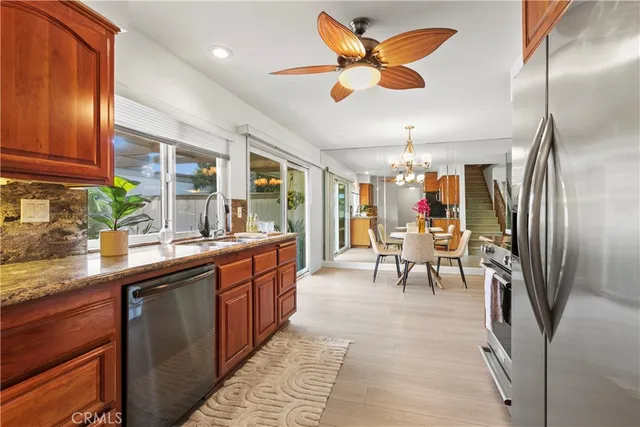 a large kitchen with stainless steel appliances kitchen island granite countertop a table chairs in it and wooden floors