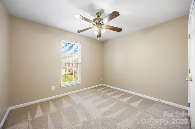 an empty room with window and ceiling fan