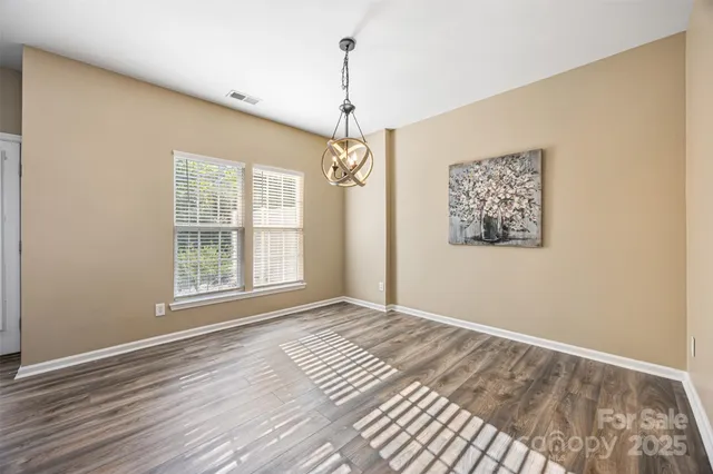 a view of an empty room with window and wooden floor