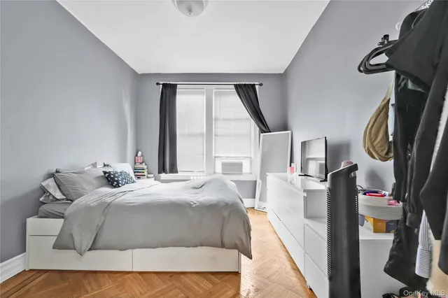 a bedroom with a bed a mirror and dresser next to a window