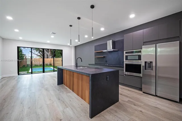 a kitchen with stainless steel appliances granite countertop a sink a stove and a wooden floors