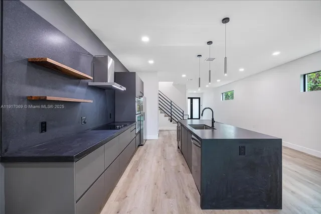 a kitchen with granite countertop a sink and white cabinets with wooden floor