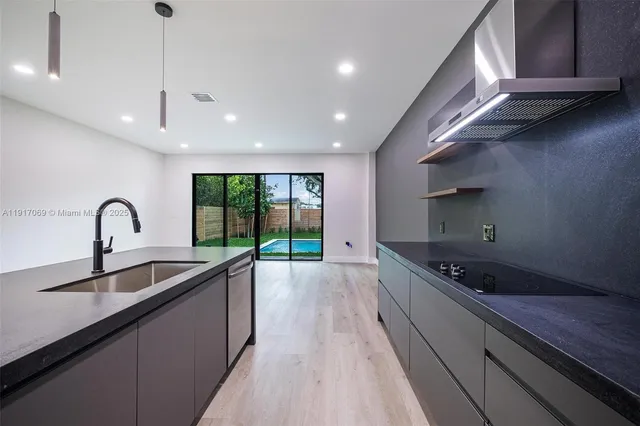 a kitchen with stainless steel appliances granite countertop a sink a stove and a wooden floors