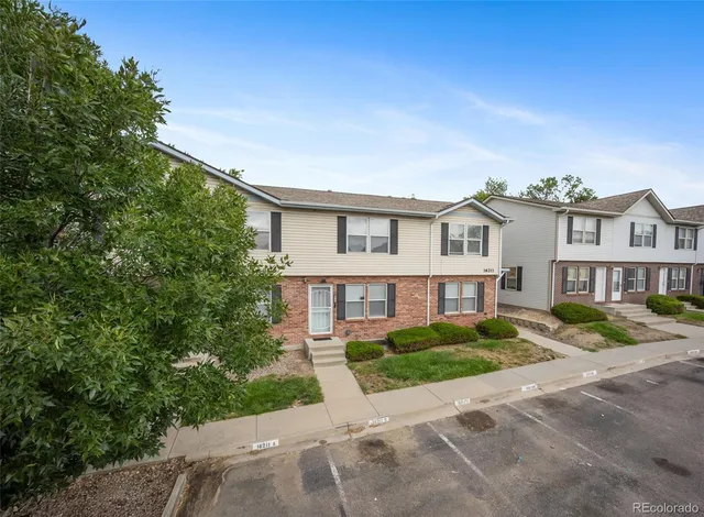 a view of a white house next to a yard with large trees