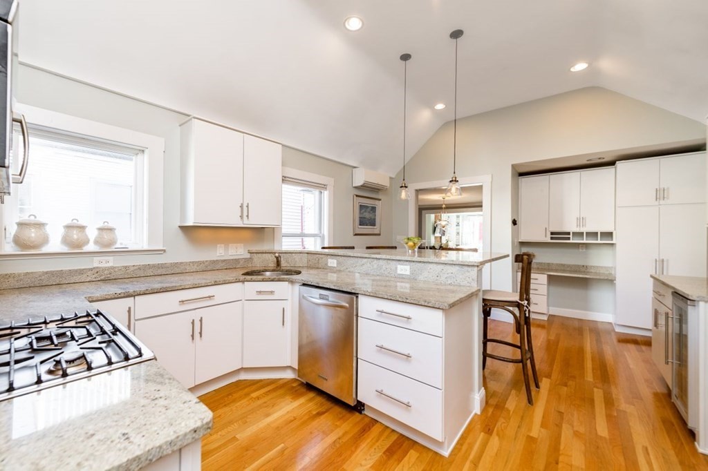 a kitchen with stainless steel appliances granite countertop a stove a sink dishwasher and a oven with white cabinets