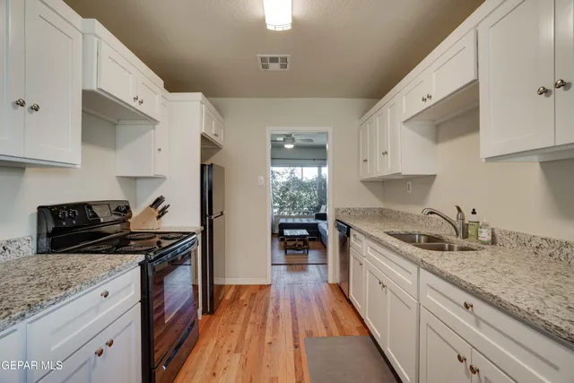 a kitchen with granite countertop stainless steel appliances a sink stove top oven and cabinets